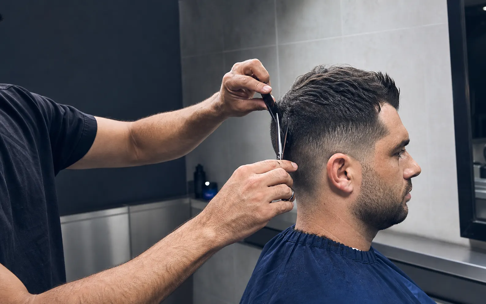 Barbero trabajando con tijera y peine sobre un corte de cabello